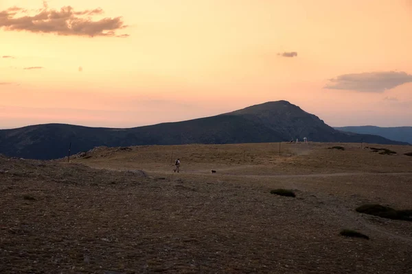 Escursionista e il suo cane camminano giù per la montagna in un tramonto incredibile. N — Foto Stock