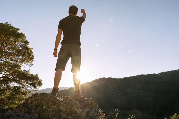 El hombre victorioso en la cima de la montaña levanta su brazo de la ra — Foto de Stock