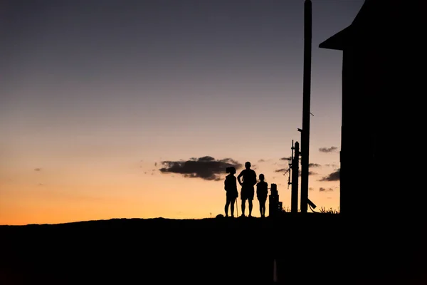 Silueta de una familia en la cima de una montaña mientras el sol es ris —  Fotos de Stock