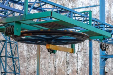 Kayak kaldırma kablosu olan paten sisteminin büyük tekerleği. Arkaplanda bulanık ağaçlar.