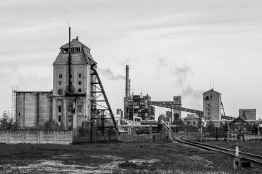 Eski bir şist işleme tesisi. Tarzlı siyah beyaz fotoğraf. Fabrikadan görünür duman, fabrika bacaları ve nakliye bandı.