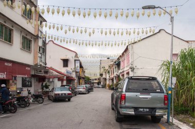 Georgetown, Malezya - 11 Aralık 2018: Bulutlu havada fener çelenkleriyle süslenmiş bir şehir caddesi. İki katlı evler. Arabalar ve motosikletler.