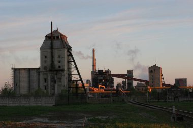 Eski bir şist işleme tesisi. Fabrikadan görünür duman, fabrika bacaları ve nakliye bandı.
