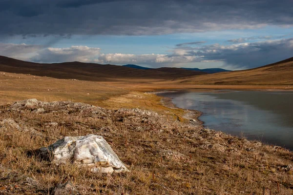 Uma grande pedra na estepe junto ao lago. Colinas além do lago . — Fotografia de Stock