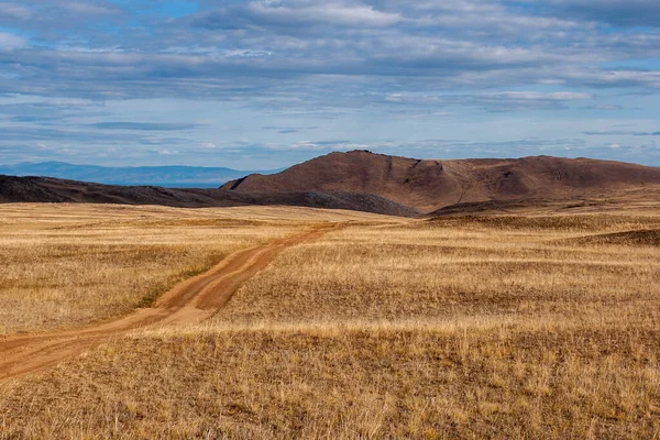Un camino en la estepa que va a las colinas. Hierba amarilla . —  Fotos de Stock