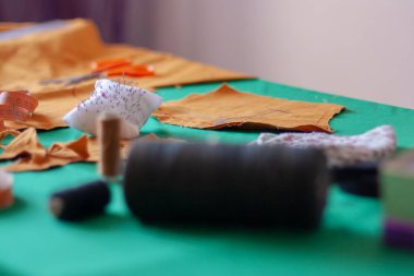 Dikiş sehpasında iğne pedi var. Terzi aletleri. Yüzeyin derinliği. İğnelere odaklan. İplik makaraları bulanık. Yatay.