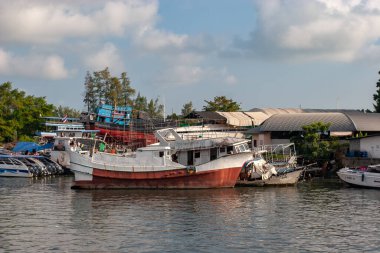 Tayland - 31 Ocak 2018: Eski paslı bir gemi nehir kıyısında duruyor. Küçük sürat teknelerinin yanında. Yatay.
