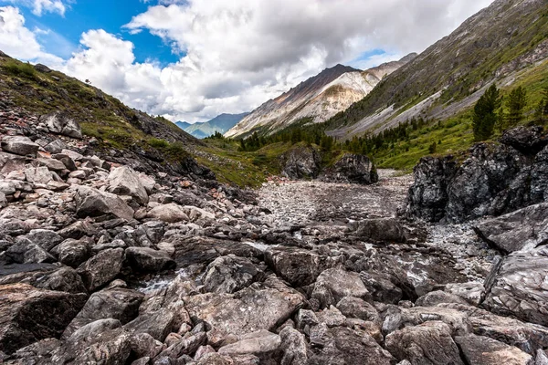 山の中で石の河床 岩の大きな断片 遠くに低い白い雲と山 — ストック写真