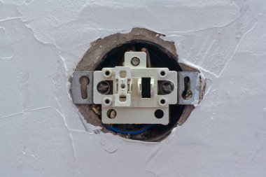 Kapağı çıkarılmış bir düğmeli bir elektrik düğmesi macun duvarına yerleştirilir. İnşaatın aşamaları. Yatay.