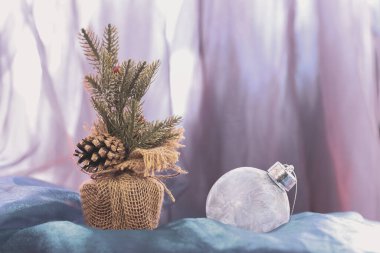 Kaba bir çuval bezinde bir koni ve kış desenli beyaz bir Noel balosu olan noel ladin dalıyla. Işık bulanık arkaplan. Uzayı kopyala Yatay.