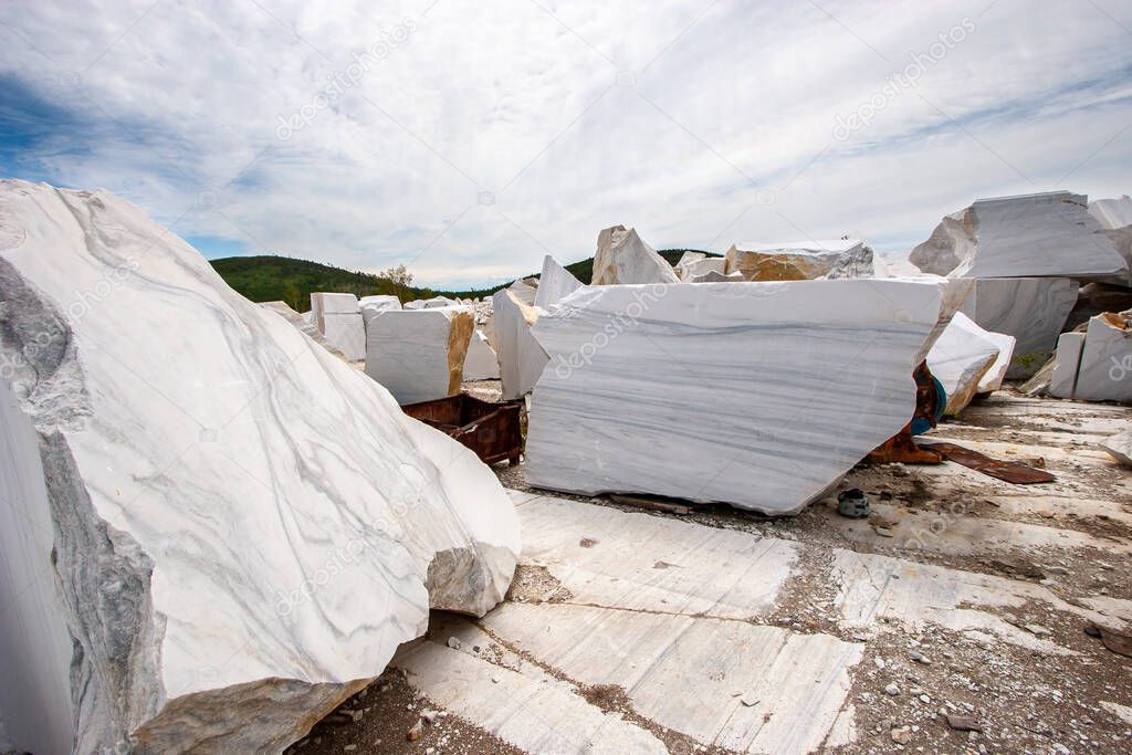 Large white marble blocks in an old abandoned quarry. Beautiful marble texture. Smooth cuts at the stones. Cloudy. Horizontal.