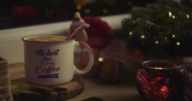 Kadın eli, sıcak bir Noel atmosferinde içeceğe pipet sokuyor..