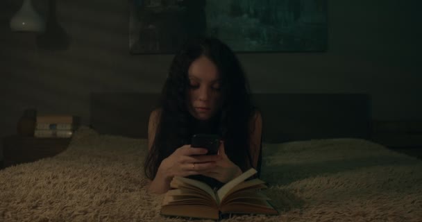 Βαρετή Νεαρή Γυναίκα Χρησιμοποιεί Smartphone Αντί Διαβάζει — Αρχείο Βίντεο
