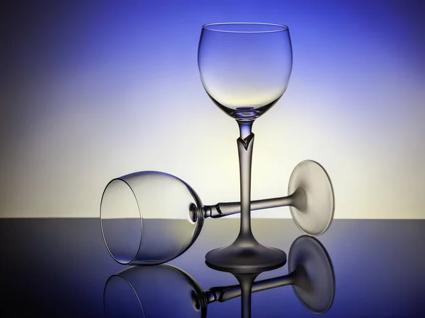 Two empty glasses on a blue-lit table, one - lies — Stok fotoğraf