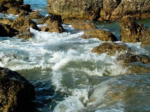 bubbling waves on a rocky pebble sea shore in the afternoon in summer