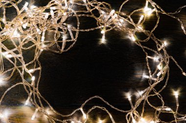 Siyah arka planda beyaz ışıkları olan çelenkler. tatil kavramı