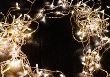 Siyah arka planda beyaz ışıkları olan çelenkler. tatil kavramı