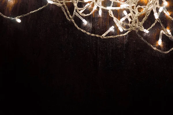 Siyah arka planda beyaz ışıkları olan çelenkler. tatil kavramı