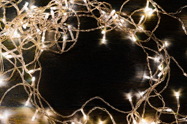 Siyah arka planda beyaz ışıkları olan çelenkler. tatil kavramı