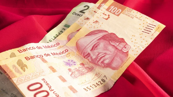 Meksika pesolarının fotoğrafı, kırmızı arkaplanda banknotlar.