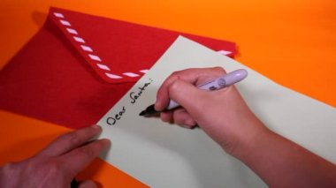 Turuncu arka planda Noel Baba 'ya mektup yollamak.