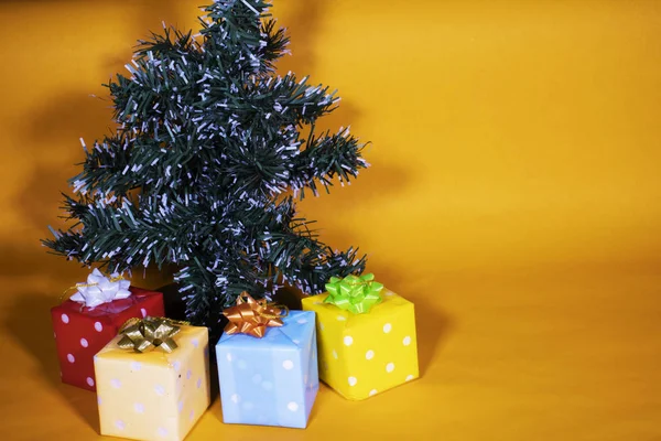 橘色背景的绿色小圣诞树 有礼物和松果 — 图库照片
