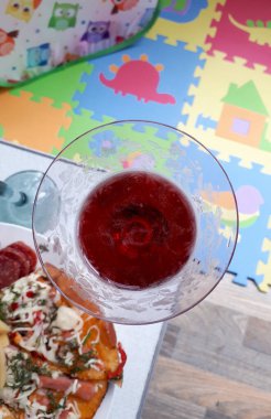 Annem için öğle yemeği molası. Kırmızı şaraplı pizza. Arka planda çocuk minderi manzaralı..