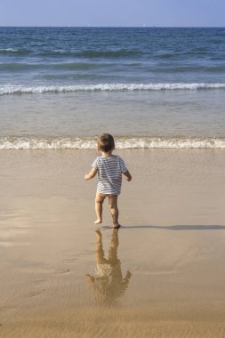 Çocuk denize çalışır.