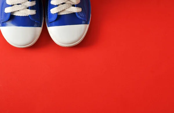Zapatillas deportivas para niños sobre fondo rojo — Foto de Stock