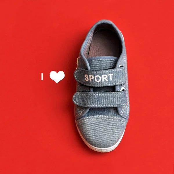 Zapatillas deportivas de bebé sobre fondo rojo. amor por el deporte — Foto de Stock