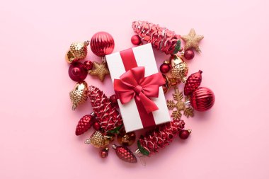 Kırmızı arkaplanlı kırmızı kurdeleli Noel hediyesi kutusu kırmızı Noel ağacı oyuncakları, altın yıldızlar ve koniler. Tatiller, yeni yıl hediyesi konsepti. Üst manzara, düz uzanma. 