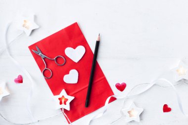 Sevgililer Günü kompozisyonu kalp, çelenk, kırmızı tebrik kartı ve kırsal beyaz arka planda bir kalem. 14 Şubat tebrik kartı. düzlük ve dikey kopyalama alanı