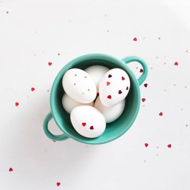 Bayramlık Paskalya. Süslü yumurtalar ve konfeti kalpli beyaz arka plan. Kopyalama alanı olan düz