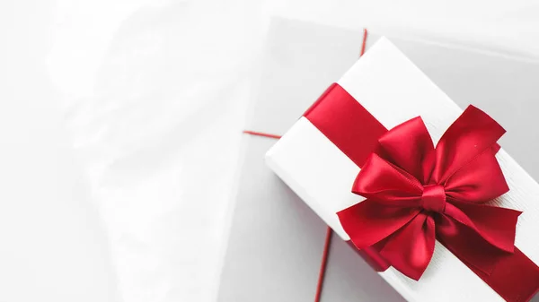 gray and white gift box/present with red ribbon on white background. Festive backdrop for holidays: Birthday, Valentines day, Women\'s day, fathers day,14 February. Flat lay banner