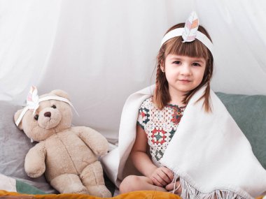 Amerikan yerlisi kostümlü küçük şirin kızlar, evde oynuyorlar, çocuk ve çocukluk kavramı.