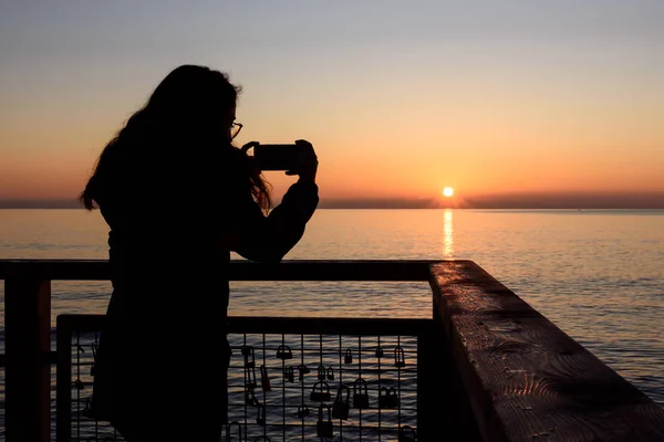 Menina fotografando com o telefone celular nascer do sol na praia de Oropesa, Valência, Espanha — Fotografia de Stock