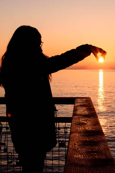 Backlit Mädchen während eines Sonnenaufgangs fängt die Sonne mit ihren Händen — Stockfoto