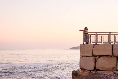 Gün batımında sahilin manzarası. Bir çift lezbiyen kız denize bakıyor.