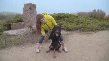Uzun kızıl saçlı hamile bir beyaz kadın güz gününü dışarıda hayvan arkadaşıyla geçiriyor. Büyük siyah doberman, sarı paltolu genç sahibine pençe atıyor. Kız evcil hayvanını eğitiyor
