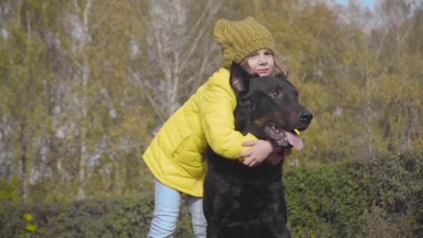 Menina Branca Sorridente Chapéu Mostarda Casaco Amarelo Abraçando Cão Parque — Vídeo de Stock