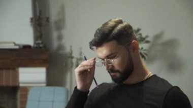 Zarif gözlük takan, kameraya bakıp gülümseyen kendine güvenen beyaz adamın portresi. Evde oturup kitap okuyan ve notlar alan yakışıklı bir delikanlının yakından çekilmiş yüzü..