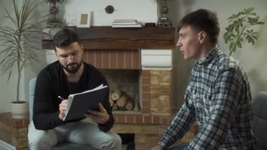 Gergin beyaz çocuk, psikoloğunun evrakları doldurmasını ve konuşmasını bekliyor. Genç adam ilk kez psikolojik muayenehaneye geldi. Bireysel terapi, sorunları çözme.
