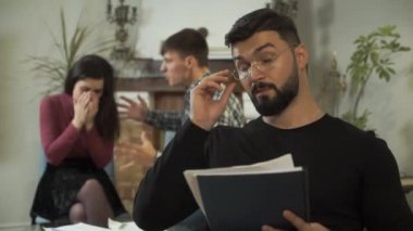 Yetişkin Kafkas psikoloğunun portresi ön planda başını sallarken müşterileri arkasından bağırıyordu. Kızgın koca arka planda karısına bağırıyor, kadın ağlıyor. Stresli çiftler terapisi.