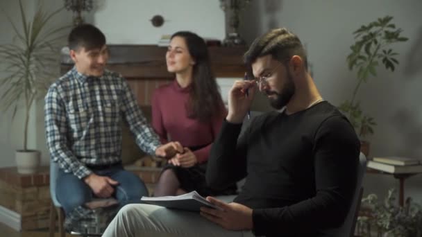 Psicólogo caucásico cansado quitándose las gafas, mirando a la cámara y sonriendo. Feliz joven besándose y abrazando a su esposa o novia en el fondo. Terapia exitosa, terapia de pareja . — Vídeos de Stock