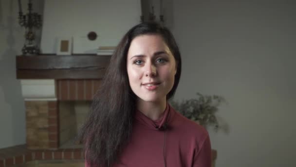 Ritratto ravvicinato di bella donna caucasica con bellissimi occhi grigi e lunghi capelli neri che parlano alla telecamera. Ragazza affascinante guardando la fotocamera e sorridente . — Video Stock