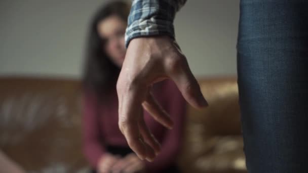 Wütender Kaukasier im Vordergrund, der seine Hand zur Faust zusammenpresst. junge Frau weint im Hintergrund und hält ihren Kopf mit der Hand. Häusliche Gewalt, Tyrannei, soziale Probleme. — Stockvideo
