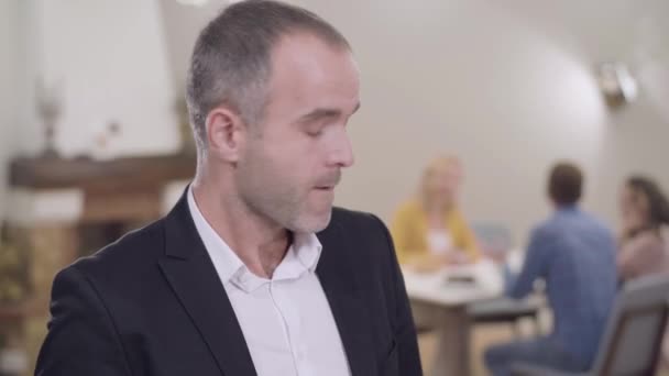 Portret van een volwassen blanke man met bruine ogen op de achtergrond van zijn familie aan tafel. Vader is ontevreden dat zijn toekomstige schoonzoon komt eten. Ontmoeting met ouders. — Stockvideo