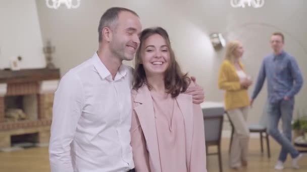 Positiver kaukasischer Vater umarmt seine schöne Tochter und lächelt. Seine Frau und sein Schwiegersohn plaudern im Hintergrund. Familientreffen, Treffen mit den Eltern. — Stockvideo