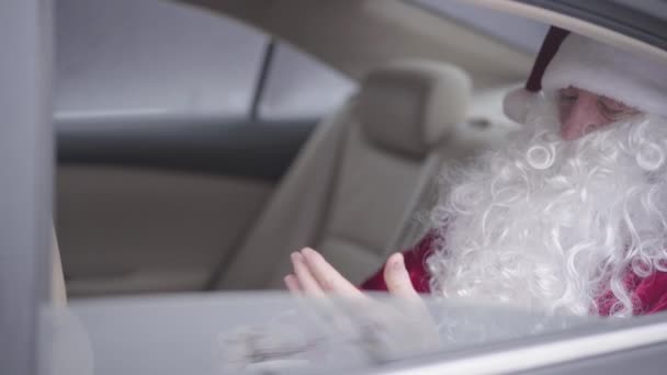 Widok z boku starego Świętego Mikołaja siedzącego w samochodzie na tylnym siedzeniu i liczącego paczkę dolarów. Święta, święta, zły Mikołaj. Bogaty facet, po wakacjach. — Wideo stockowe