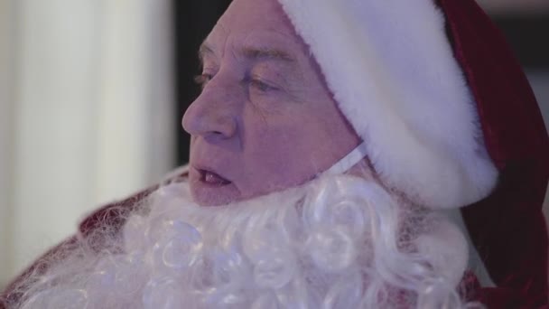 Side view of tired old man in Santa Claus costume drinking beer and watching TV. Close-up portrait of bad Santa Claus. Alcoholism, depression, negativism. — Stock Video